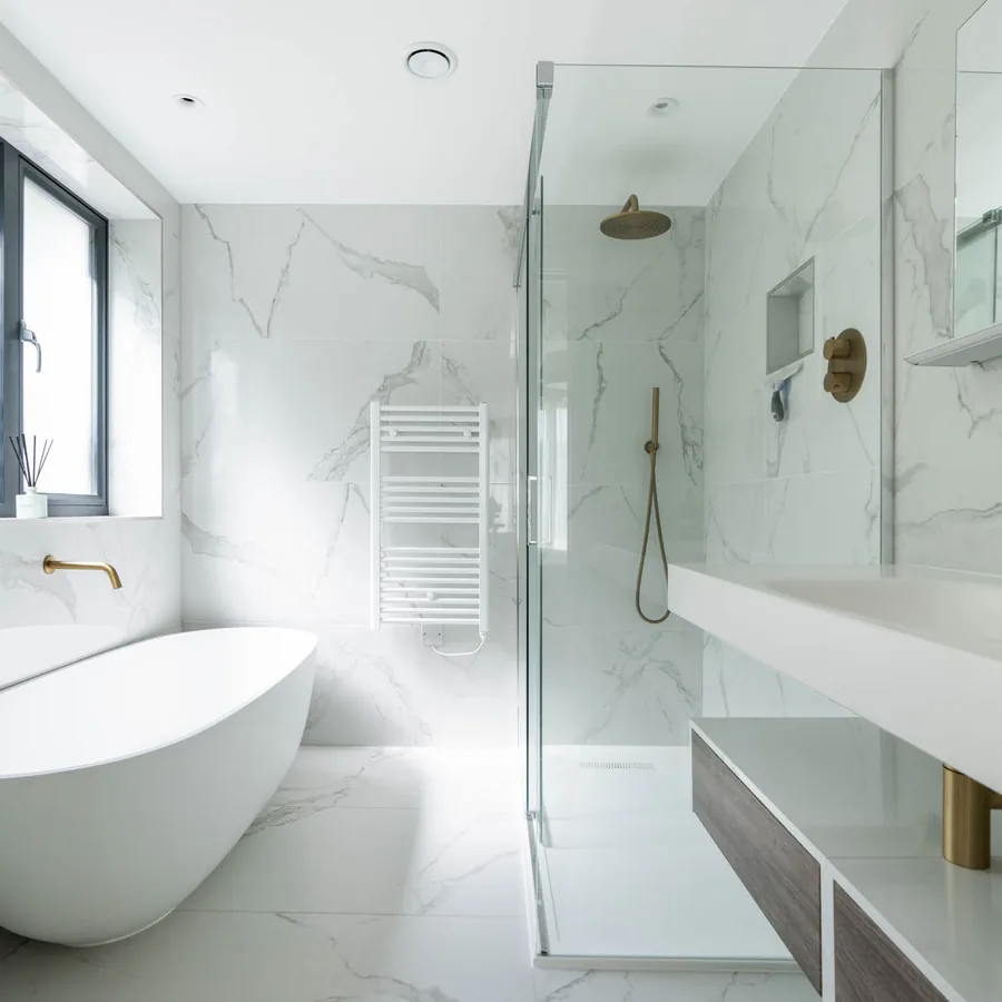 A freestanding bath in a marble bathroom with brass fittings