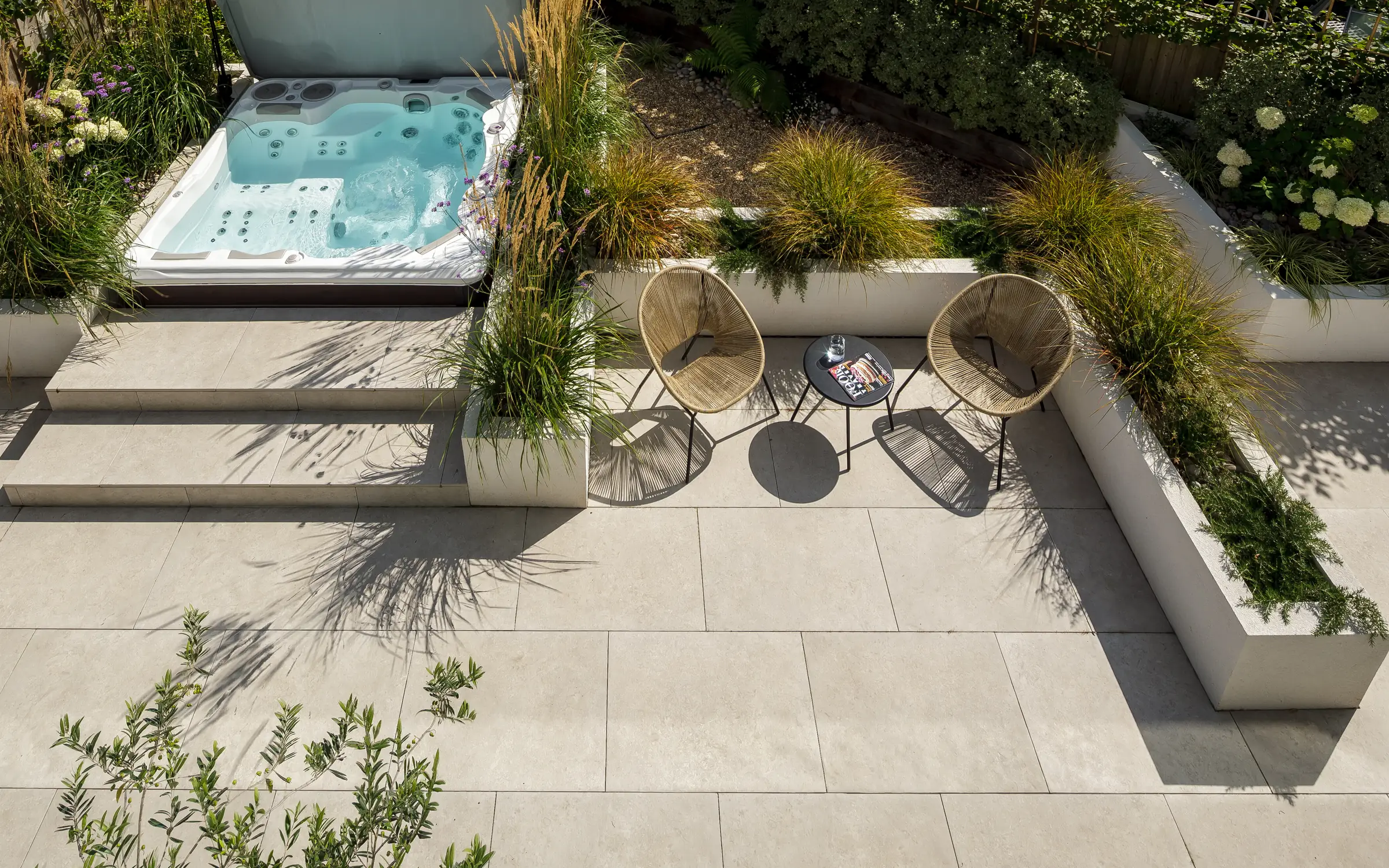 The private hot tub set flush into the courtyard paving, with grasses, raised beds and seating around it